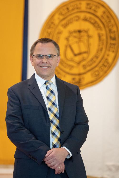 President Eric Boynton stands in front of the Beloit College seal.